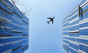 Airplane Near Blue and Grey Building