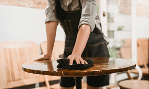 Person Cleaning Table in Cafe